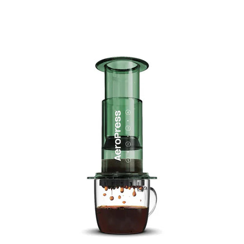 Green AeroPress coffee maker with a glass container on a white background