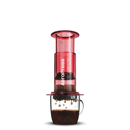 Red AeroPress coffee maker with a glass container on a white background