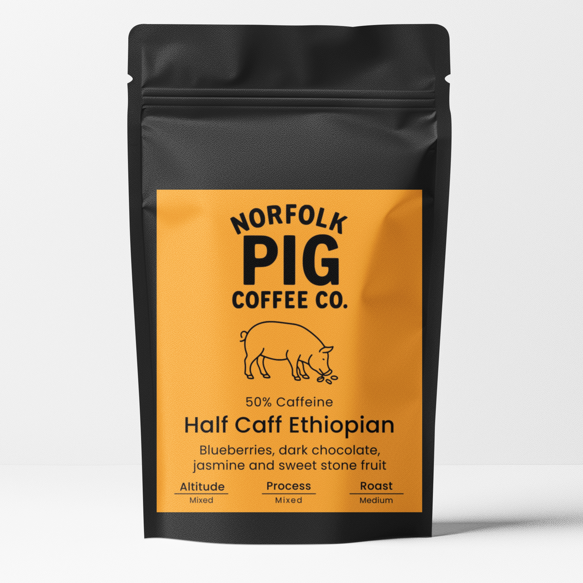 A black stand-up pouch of Norfolk Pig Coffee Co. Half Caff Ethiopian coffee with a bright orange label, shown on a light gray background.